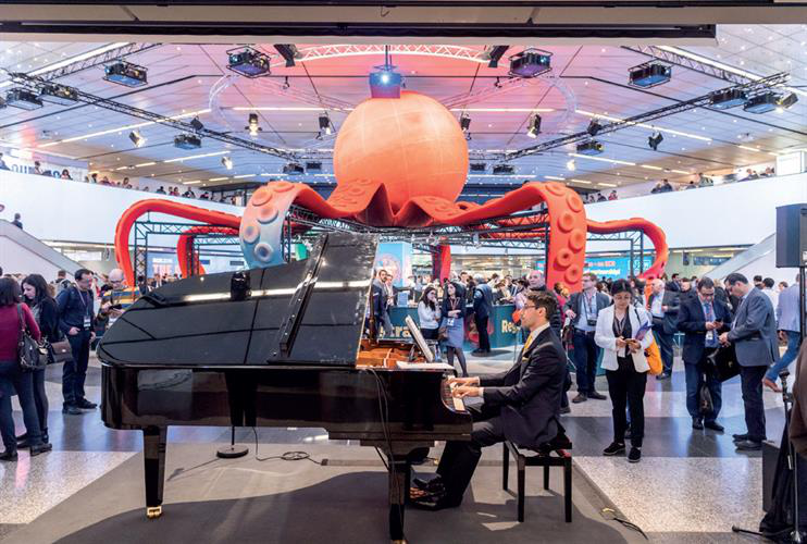 Large octopus sculpture behind man playing piano